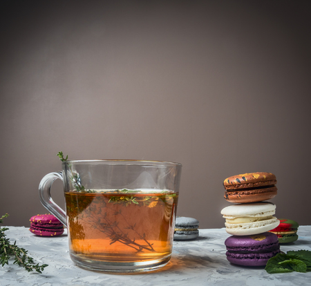 tea with herbs, cumin, mint, appetizing macaroons, on a white table, on a blurry background, space for textの写真素材