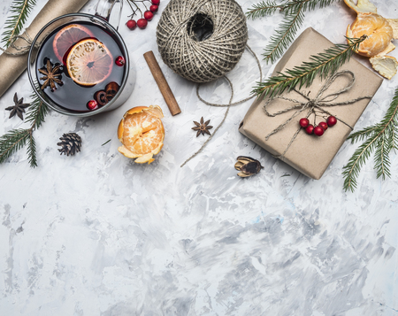 Christmas concept, mulled wine and ingredients for its preparation, packing paper, string, gift in a box, tangerines, cinnamon sticks, on a white rustic background, space for textの写真素材