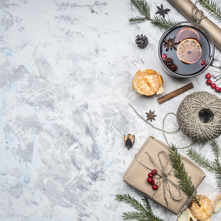 Christmas concept, mulled wine and ingredients for its preparation, packing paper, string, gift in a box, tangerines, cinnamon sticks, on a white rustic background, space for textの写真素材