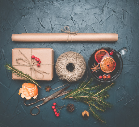 New Year or Christmas concept, roll of paper, gift, twine, mulled wine cup, vintage scissors, sprigs of Christmas tree, mandarins, top view, space for textの写真素材