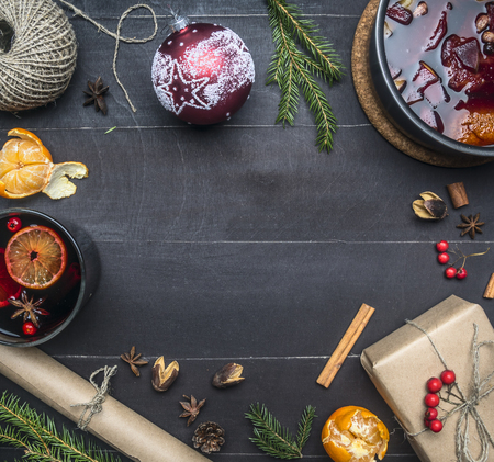 concept of the new year or Christmas, the preparation of mulled wine, frame of Christmas decorations, a gift in wrapping paper, mandarins, twine, Christmas tree branches, on wooden rustic backgroundの写真素材
