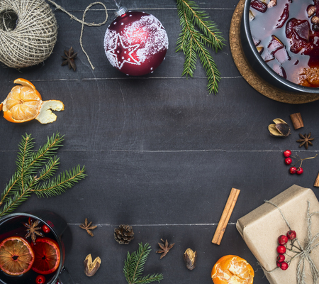 New Year or Christmas composition, string for packing, tangerines, toy, mulled wine, gift in the package, decorated with berries, Christmas tree branches, on  dark rustic wooden background, text placeの写真素材