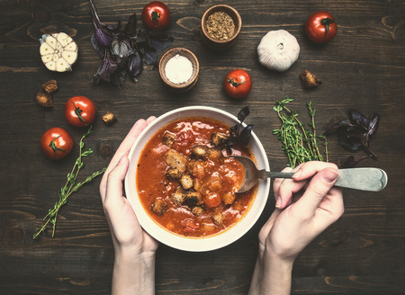 composition of ingredients for the preparation of tomato soup, cherry tomatoes, basil, garlic, herbs, a girl with a spoon eats a soup from a white plateの写真素材
