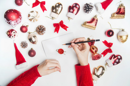 Christmas or New Year composition, toys, cones, ornaments, lined around an envelope that the girl signs in a red sweater, on a white background, the top viewの写真素材