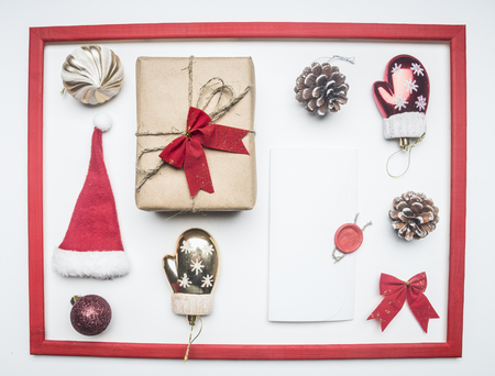 frame, Christmas or New Year composition, Santa Claus hat, lollipops, gift in a box with a bow, red packing paper, lined on a white background, top view, flat layの写真素材