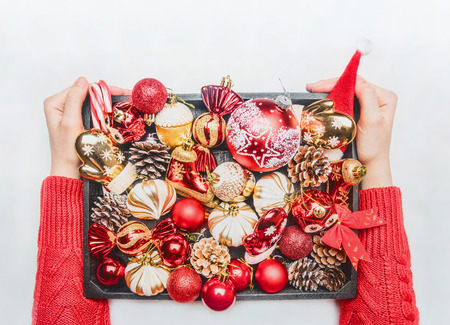 girl in a red New Year's sweater holds a box of Christmas toys in her hands, a top viewの写真素材