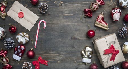 Christmas or Christmas concept, various Christmas tree toys, a gift in wrapping paper, an envelope with congratulations, a lined frame on a rustic wooden background, space for textの写真素材