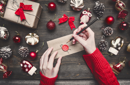 Christmas composition, the girl holds a envelope in her hands, toys and ornaments lie around her, on a wooden rustic backgroundの写真素材