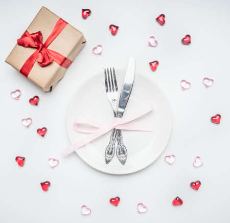 composition for Valentine's day knife and fork tied with ribbon on a plate with decorative heartsの写真素材