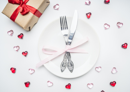 composition for Valentine's day knife and fork tied with ribbon on a plate with decorative heartsの写真素材