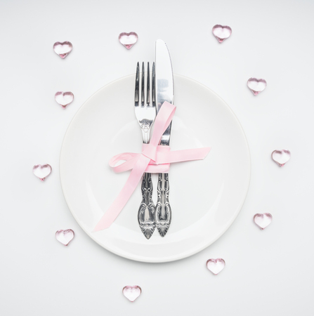 composition for Valentine's day knife and fork tied with ribbon on a plate with decorative heartsの写真素材