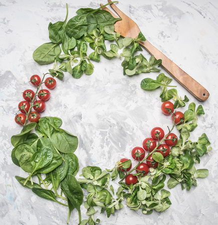 concept of cooking vegetarian food, cherry tomatoes, various salad varieties, spinach seasoning, spices, olive oil, salad fork, lined with space for textの写真素材