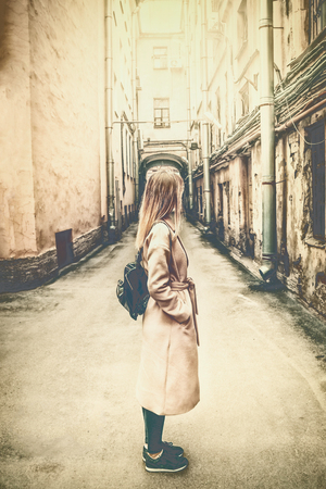 lifestyle photography, a girl in a pink coat is standing in the ancient courtyard of a European city, the sun's raysの写真素材