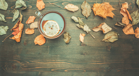 autumn composition, yellow leaves, a cup of hot tea with lemon on a wooden background, space for text flat layの写真素材