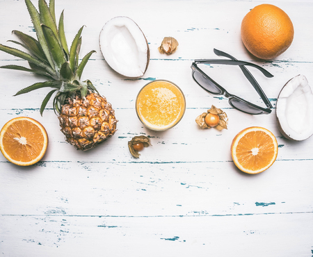 summer concept, pineapples, orange juice, sunglasses, coconut, on a white rustic wooden background, place for text flat layの写真素材
