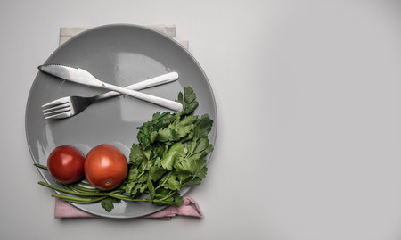 simple food, tomatoes, parsley and penne pasta on a gray plate, lined on a white background, top view, space for textの写真素材