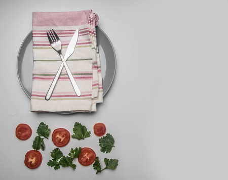 simple food, tomato, parsley and penne pasta on a gray plate on a napkin, lined on a white background, top view, space for textの写真素材