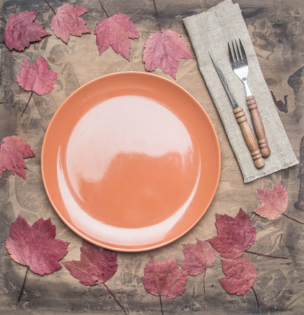 autumn composition, yellow leaves, small pumpkins lined around a brown plate, space for text flat layの写真素材