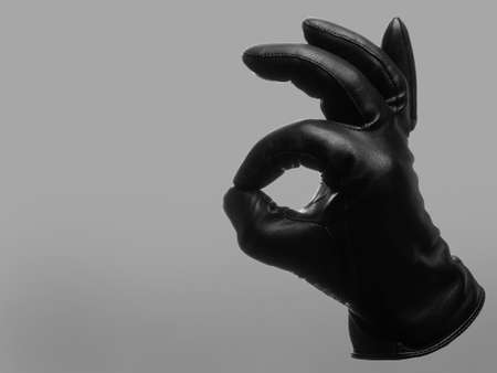 black leather glove shows OK gesture. isolated neutral background. copy spaceの写真素材