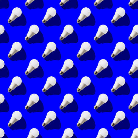 seamless pattern. white lightbulbs is right up on dark blue background. geometric arrangement of...