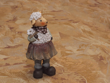 Ceramic sheep statuette on the textile background photoの写真素材