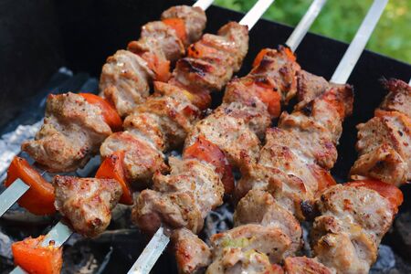 Kebab and mushrooms grilling on the skewers on the charcoals photoの写真素材