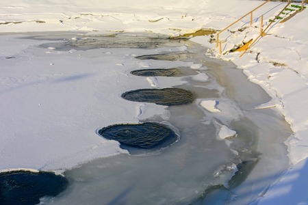 Warm water on the ice of a frozen lake covered with ice in winterの写真素材