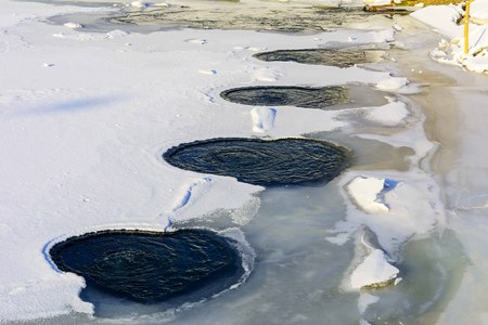 Warm water on the ice of a frozen lake covered with ice in winterの写真素材