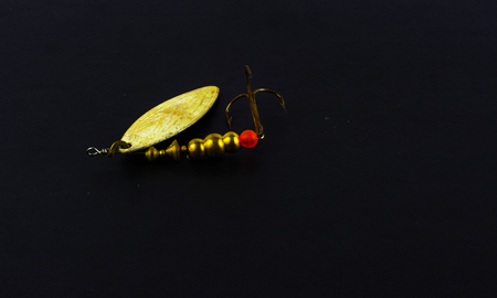 Copies of fishing metal spoon baits. Bait for fishing in the shape of a spoon with a hook on a black background.の写真素材