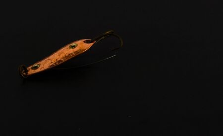 Copies of fishing metal spoon baits. Bait for fishing in the shape of a spoon with a hook on a black background.の写真素材