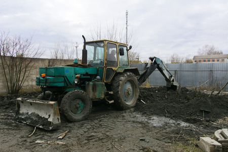 An old Soviet tractor digs and loads waste stone processing near the shop