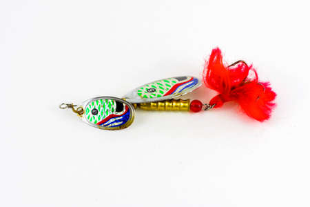 Exhibition of pirated copies of fishing metal spoon baits. Bait for fishing in the shape of a spoon with a hook on a white backgroundの写真素材