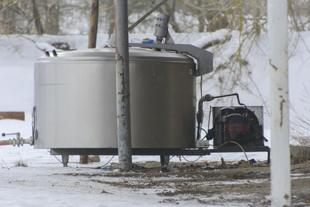 A large old tank for collecting milk in an abandoned and destroyed factory against a background of white snow in winter. Destruction and vandalism. Ukraine.の写真素材
