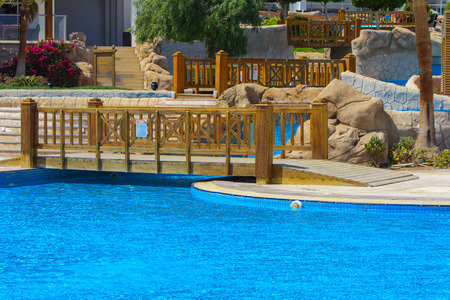 Sharm el-Sheikh, Egypt - March 14, 2018.  Beautiful pool in Cyrene Grand Hotel with clear blue water on the background of the sea, blue sky and green palm trees. Beach chaise longue.のeditorial素材