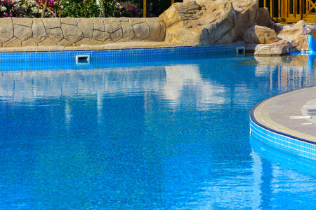 Sharm el-Sheikh, Egypt - March 14, 2018.  Beautiful pool in Cyrene Grand Hotel with clear blue water on the background of the sea, blue sky and green palm trees. Beach chaise longue.のeditorial素材
