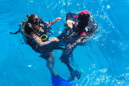 Divers on the clear and turquoise Red Sea on immersion in beautiful corals and colorful fish. The teacher teaches the student the rules of immersion in water. Summer, vacation. Egyptの写真素材