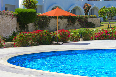 Sharm el-Sheikh, Egypt - March 14, 2018.  Beautiful pool in Cyrene Grand Hotel with clear blue water on the background of the sea, blue sky and green palm trees. Beach chaise longue.のeditorial素材