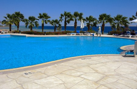 Sharm el-Sheikh, Egypt - March 14, 2018. Relaxation next to a beautiful swimming pool with clear clear blue water. Attendants near the pool. Cyrene Grand Hotel.のeditorial素材