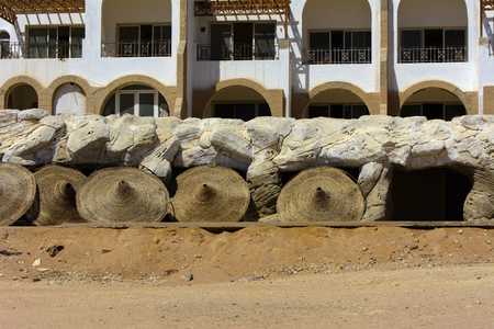 Sharm el-Sheikh, Egypt - March 14, 2018. Fragments of an unfinished construction and abandoned hotel on the Red Sea on a background of yellow sand and blue sky. Travel rest on a summer day outdoors.のeditorial素材