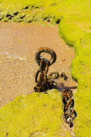 An old rusty chain is thrown on the seashore against a background of yellow sand.の写真素材