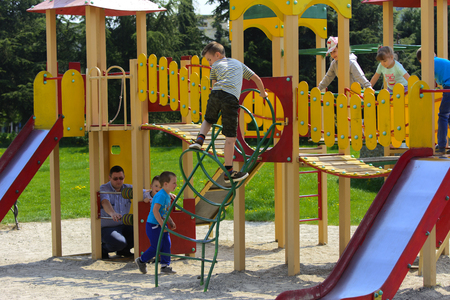 Khust, Ukraine - April 22, 2018. Little children run around and play in the playground. Game center for a young child. Little girl is playing outdoors. The concept of summer children's entertainment.のeditorial素材