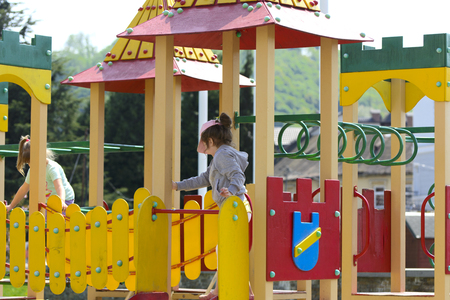 Khust, Ukraine - April 22, 2018. Little children run around and play in the playground. Game center for a young child. Little girl is playing outdoors. The concept of summer children's entertainment.のeditorial素材