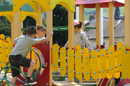 Khust, Ukraine - April 22, 2018. Little children run around and play in the playground. Game center for a young child. Little girl is playing outdoors. The concept of summer children's entertainment.のeditorial素材
