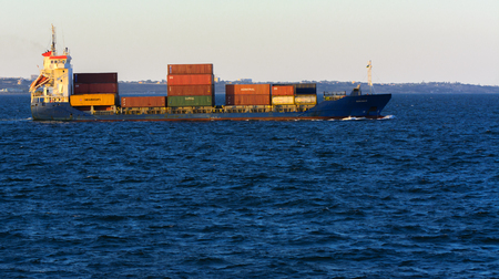 Odessa, Ukraine - August 08, 2018. A large cargo ship transports containers in the open sea in the evening soft sunlight against a blue sky. The concept of freight traffic on the Black Sea, Ukraine.のeditorial素材