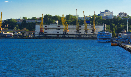 Odessa, Ukraine - August 8, 2018. Big working cranes for loading containerships and various cargoes to the ships at the shipyard against a beautiful evening blue sky in soft colors. Cargo deliveryのeditorial素材