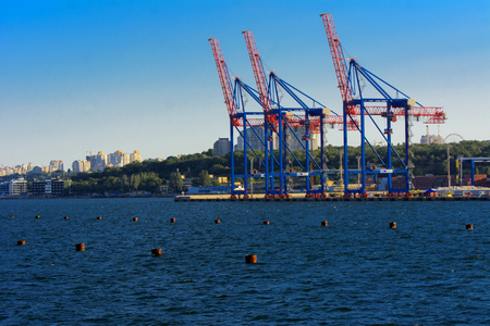 Odessa, Ukraine - August 8, 2018. Big working cranes for loading containerships and various cargoes to the ships at the shipyard against a beautiful evening blue sky in soft colors. Cargo deliveryのeditorial素材