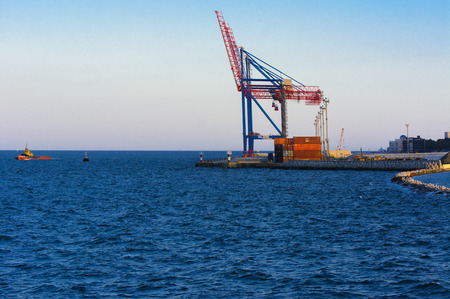 Odessa, Ukraine - August 8, 2018. Big working cranes for loading containerships and various cargoes to the ships at the shipyard against a beautiful evening blue sky in soft colors. Cargo deliveryのeditorial素材