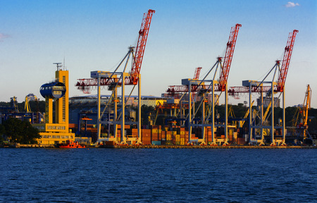 Odessa, Ukraine - August 8, 2018. Big working cranes for loading containerships and various cargoes to the ships at the shipyard against a beautiful evening blue sky in soft colors. Cargo deliveryのeditorial素材