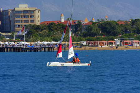 Alanya, Turkey - October 05, 2018. A small high-speed yacht with tourists passes along the coast against the blue sky. Photos of the ship from the sea. The concept of summer holidays, sports, tourismのeditorial素材