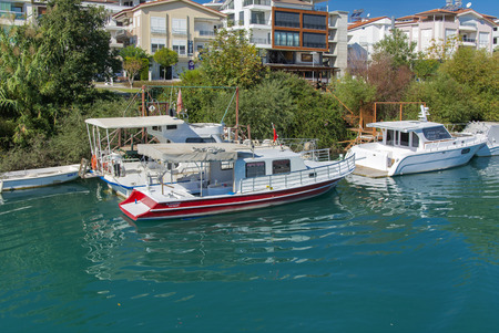 Alanya, Turkey - October 05, 2018. A small speedboat moored at the pier along the coast against a blue sky. Photos of the ship from the sea. The concept of summer holidays, sports, tourismのeditorial素材